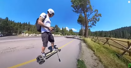 A person wearing a helmet and backpack is riding an electric skateboard.