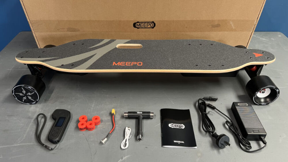 Complete Meepo electric skateboard package including board, remote control, charger, maintenance tools and user manual on display