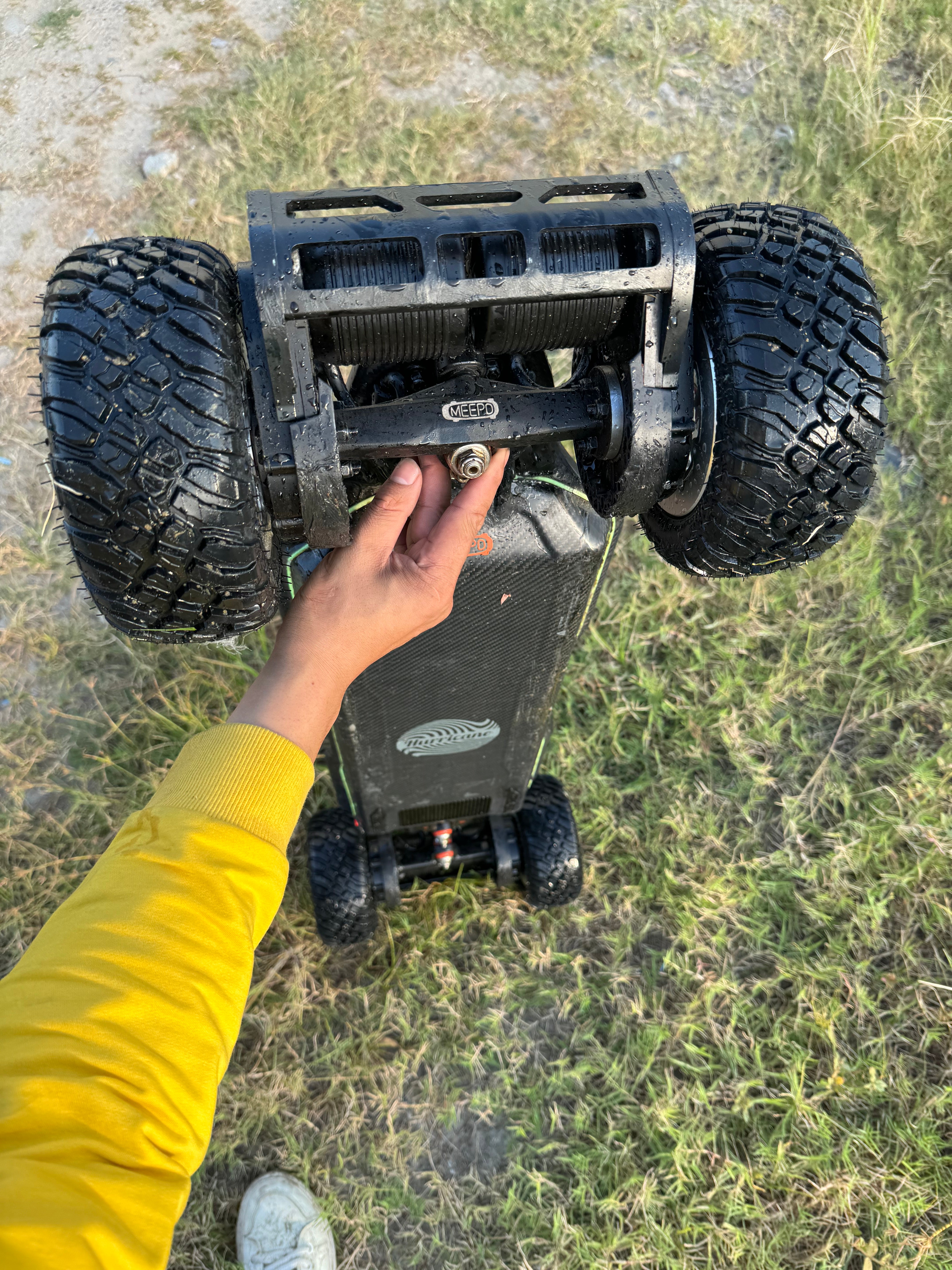 Close-up of a person holding an electric skateboard with 200mm off-road tires.