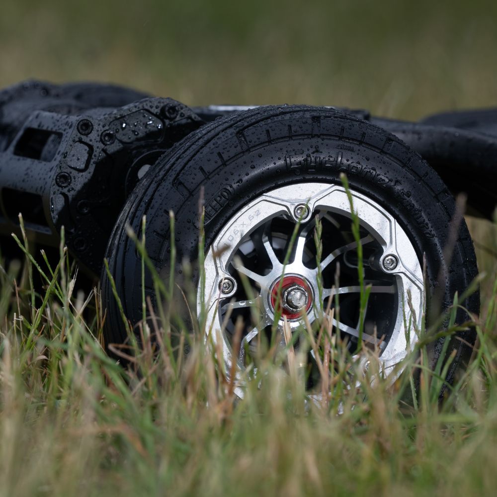 Close-up of Meepo skateboard wheel with rugged tread in wet grass environment