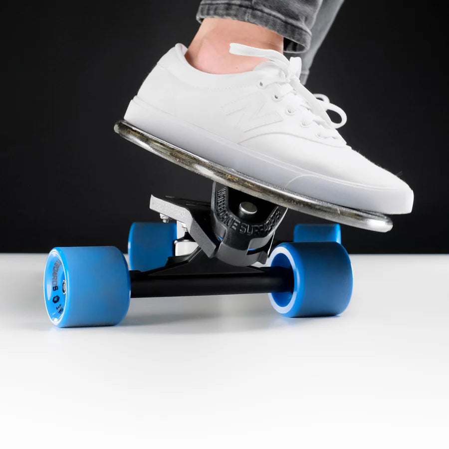 Skateboard with Waterborne Surf Adapter and blue wheels under a foot.