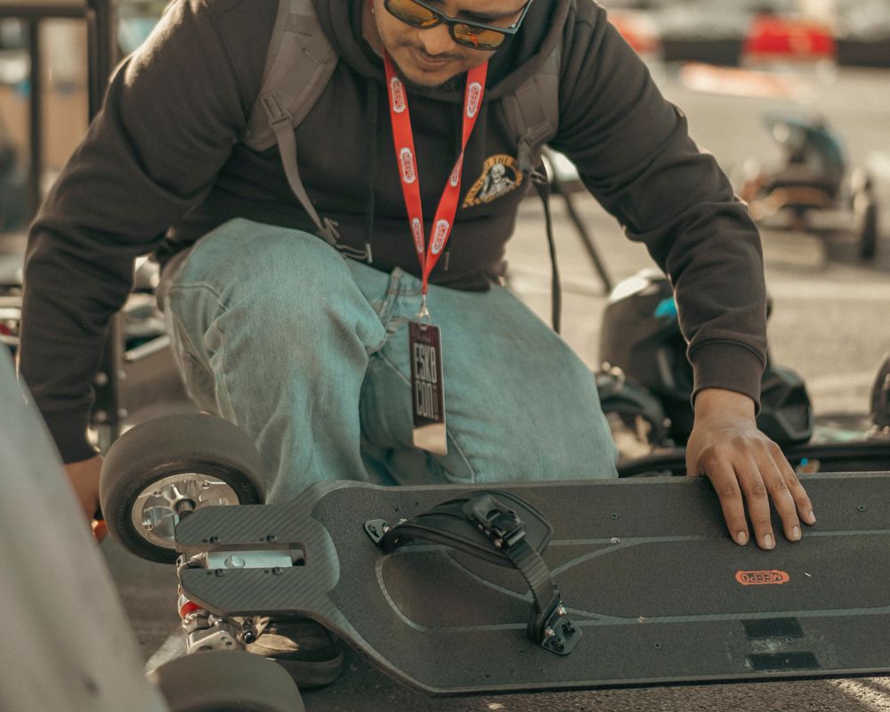 Rider adjusting Meepo Monsoon Legacy Raceboard chassis with detailed focus.