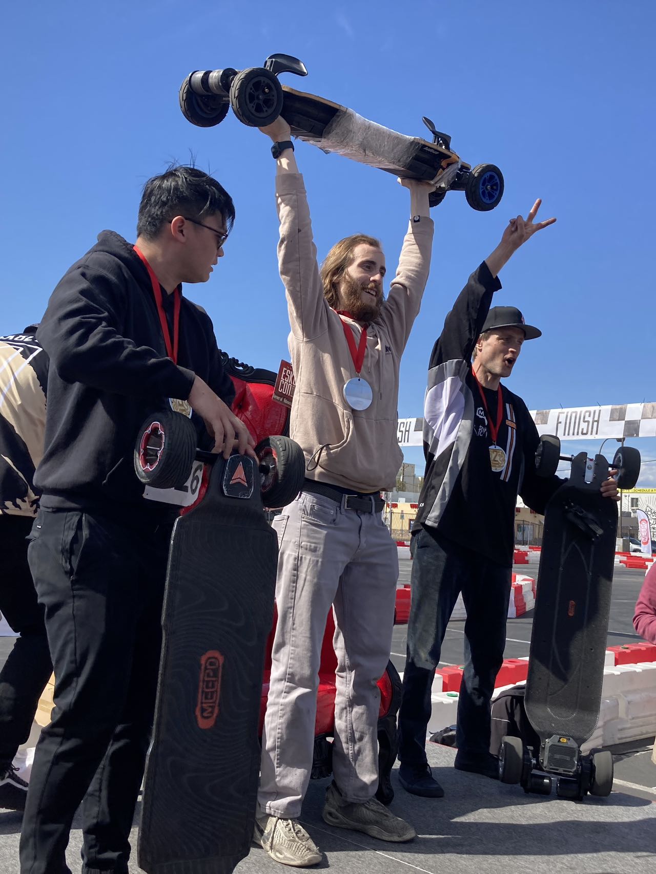 Rider celebrating victory with Meepo Monsoon Legacy Raceboard at competition finish line.