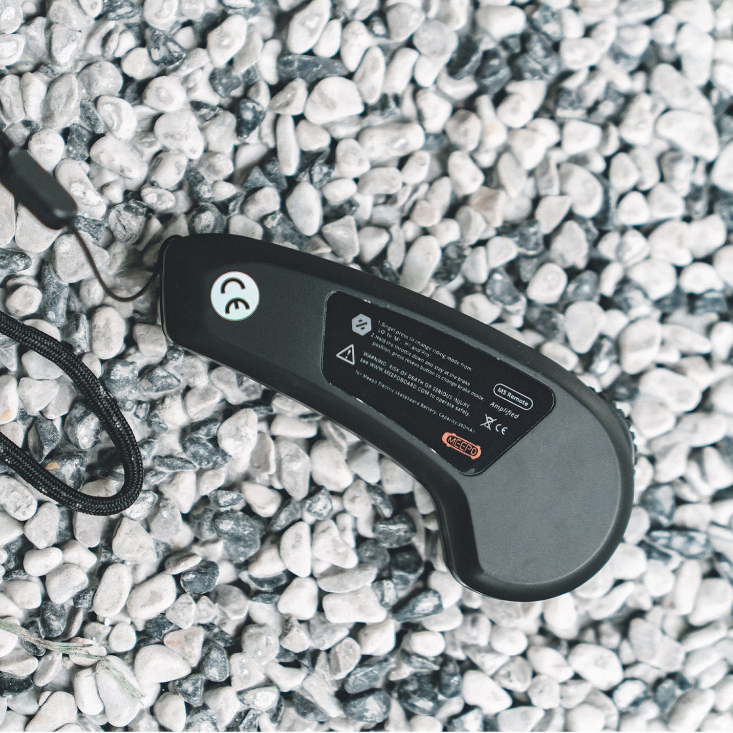Meepo M5 remote control on pebble surface with ergonomic design and control buttons.